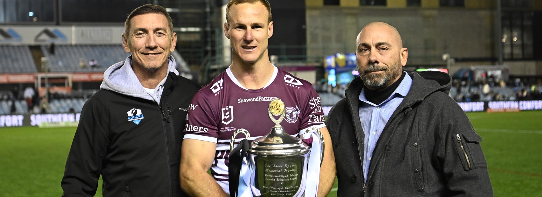 Mat and Don Rogers present Manly captain Daly Cherry-Evans with the Steve Rogers Memorial Trophy, in honour of their late, great father and Sharks Immortal.